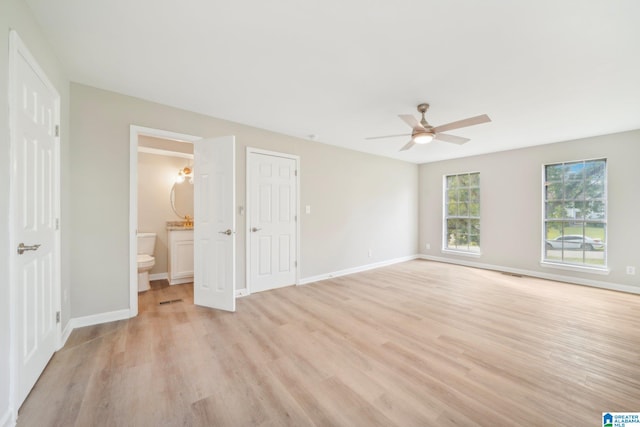 unfurnished bedroom featuring ceiling fan, ensuite bath, and light wood-type flooring