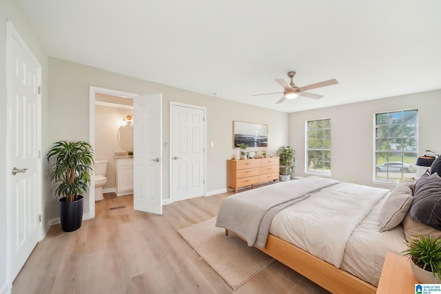 bedroom with light hardwood / wood-style floors, ceiling fan, and connected bathroom