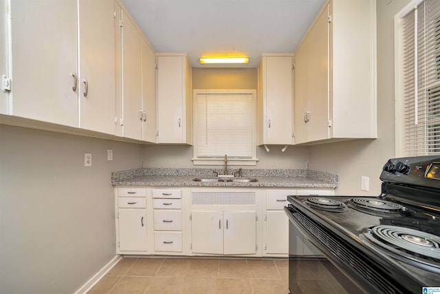 kitchen with light tile patterned floors, black range with electric cooktop, sink, and light stone counters