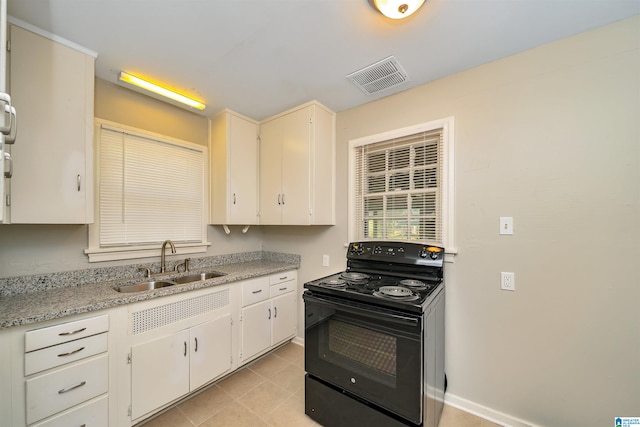 kitchen with white cabinets, black / electric stove, light tile patterned floors, sink, and light stone countertops