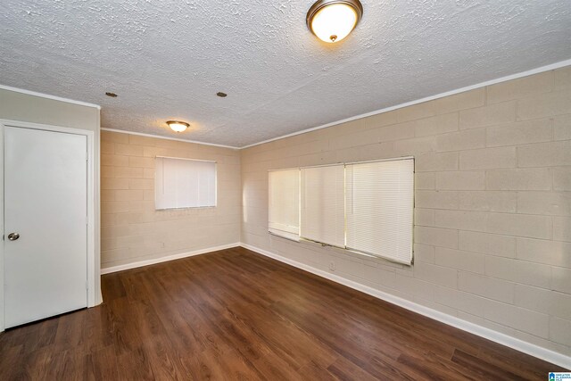 empty room with dark hardwood / wood-style flooring, a textured ceiling, and ornamental molding