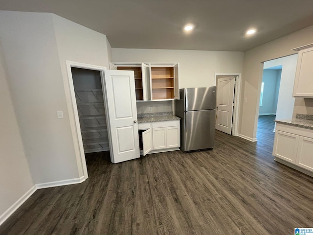 kitchen featuring white cabinetry, stainless steel refrigerator, dark hardwood / wood-style floors, and light stone counters