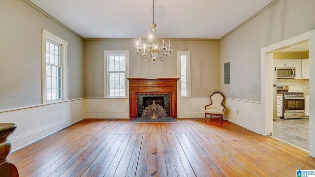 unfurnished living room featuring electric panel, a chandelier, light hardwood / wood-style flooring, and ornamental molding