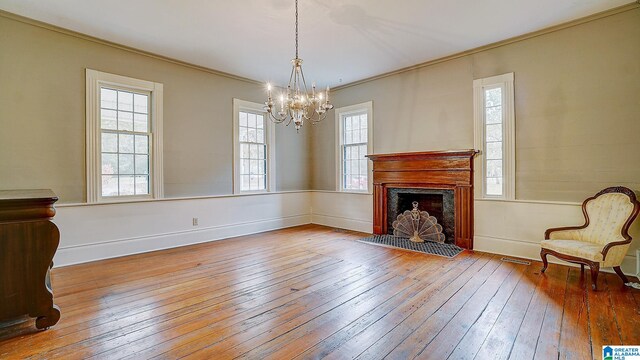 living room with light wood-type flooring, an inviting chandelier, and ornamental molding