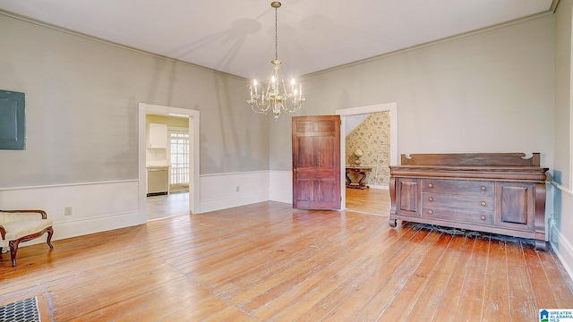 interior space with light hardwood / wood-style flooring, crown molding, and an inviting chandelier