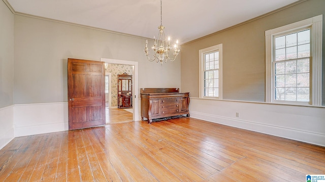 unfurnished room with light hardwood / wood-style floors, a chandelier, and crown molding