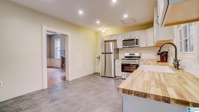 kitchen featuring light hardwood / wood-style floors, white cabinetry, sink, appliances with stainless steel finishes, and butcher block countertops