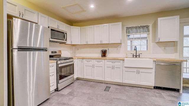 kitchen featuring white cabinets, appliances with stainless steel finishes, sink, and backsplash