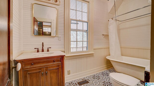 bathroom with toilet, vanity, wooden walls, and tile patterned flooring