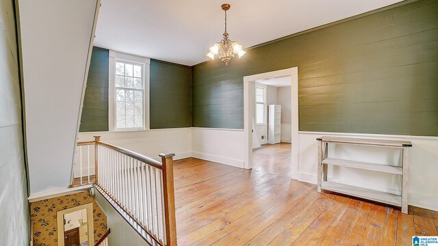 hallway featuring light wood-type flooring and an inviting chandelier