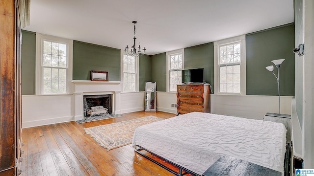 bedroom with multiple windows, light wood-type flooring, and a notable chandelier