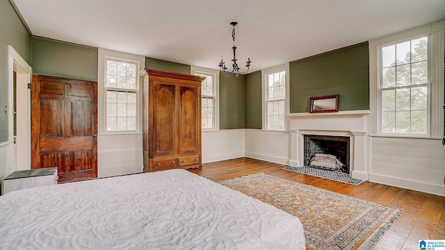 bedroom featuring light hardwood / wood-style floors, multiple windows, and an inviting chandelier