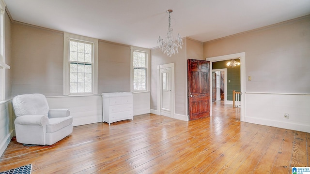 living area featuring hardwood / wood-style floors, crown molding, and a notable chandelier