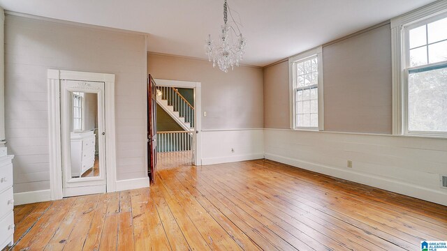 unfurnished dining area featuring light hardwood / wood-style floors, a chandelier, and crown molding