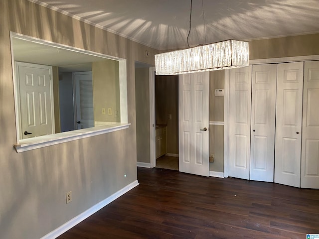 unfurnished bedroom featuring dark wood-type flooring and an inviting chandelier