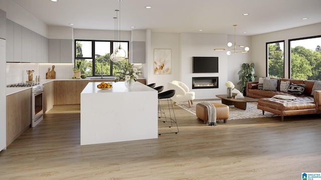 kitchen featuring light wood-type flooring, stainless steel range with gas stovetop, pendant lighting, and a center island