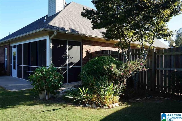 view of home's exterior featuring a sunroom and a yard