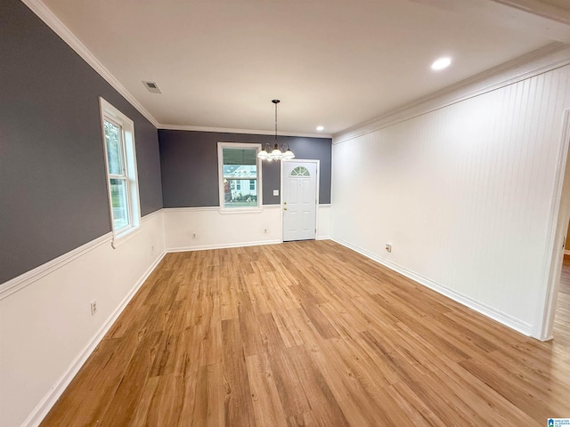 unfurnished dining area with light hardwood / wood-style flooring, an inviting chandelier, and ornamental molding