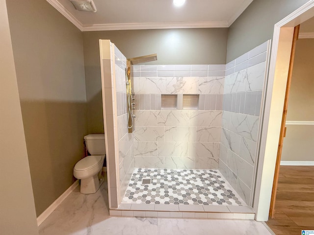 bathroom featuring toilet, ornamental molding, and tiled shower