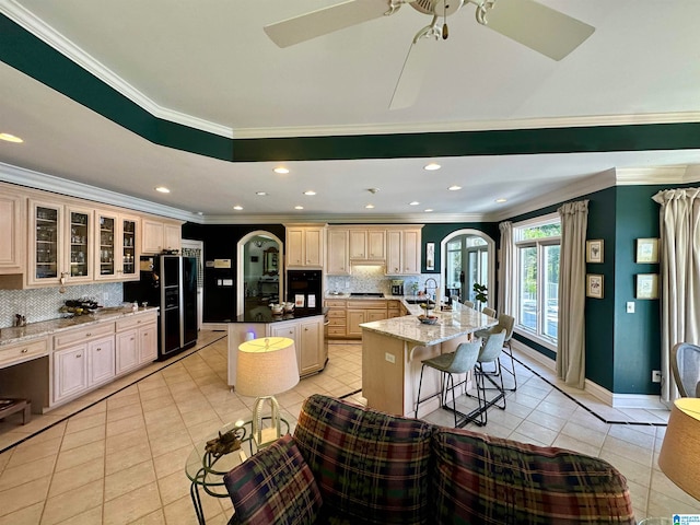 kitchen featuring an island with sink, crown molding, and tasteful backsplash