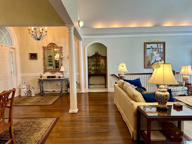 living room featuring hardwood / wood-style floors, ornate columns, an inviting chandelier, and ornamental molding