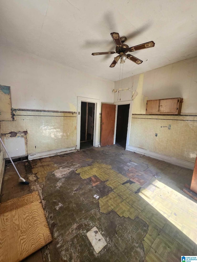 interior space with tile walls, a baseboard radiator, and ceiling fan