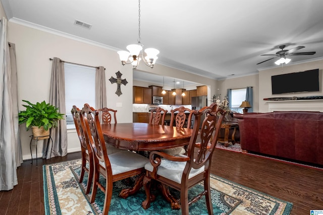 dining room with ornamental molding, ceiling fan with notable chandelier, and dark wood-type flooring