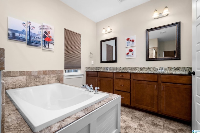 bathroom with tile patterned flooring, vanity, and tiled bath