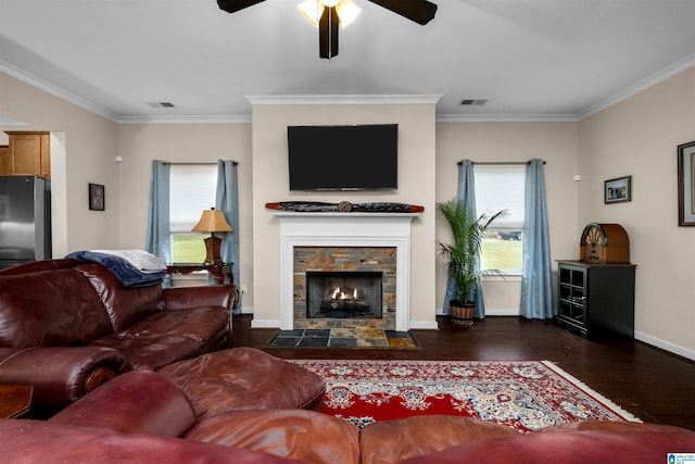 living room with dark hardwood / wood-style floors, ceiling fan, a stone fireplace, and ornamental molding