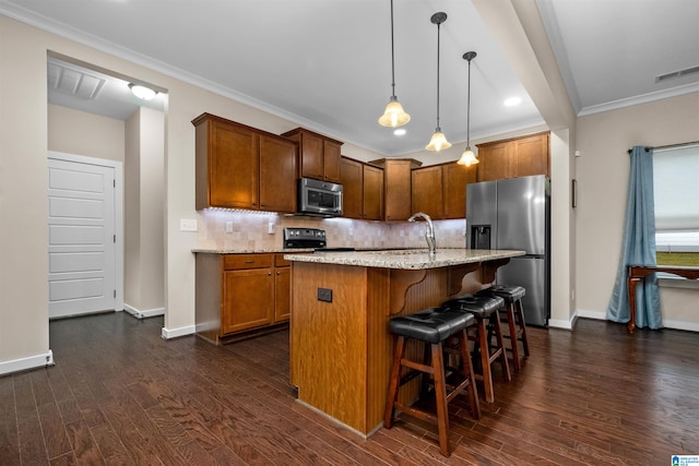 kitchen featuring dark hardwood / wood-style flooring, an island with sink, stainless steel appliances, and decorative light fixtures