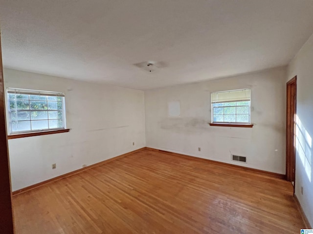 unfurnished room featuring wood finished floors, plenty of natural light, and baseboards