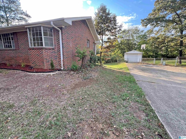 view of property exterior featuring brick siding, a garage, an outbuilding, and fence
