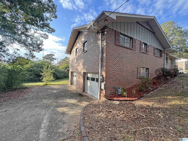 view of property exterior with brick siding, an attached garage, concrete driveway, and board and batten siding