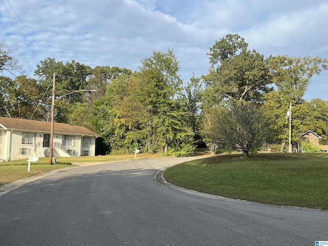 view of asphalt road with street lighting and curbs