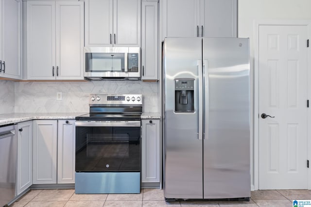 kitchen featuring gray cabinetry, light tile patterned floors, backsplash, and appliances with stainless steel finishes