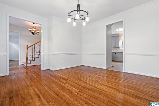 empty room with light hardwood / wood-style floors, an inviting chandelier, and ornamental molding