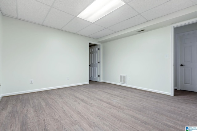 empty room featuring a drop ceiling and light hardwood / wood-style flooring