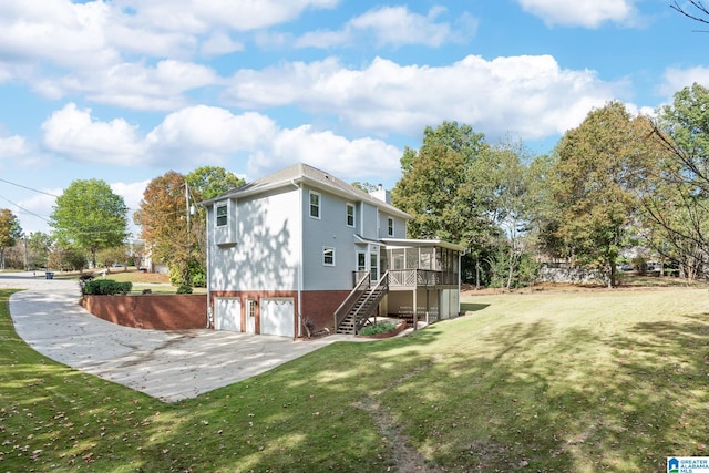 rear view of property with a garage, a sunroom, and a yard