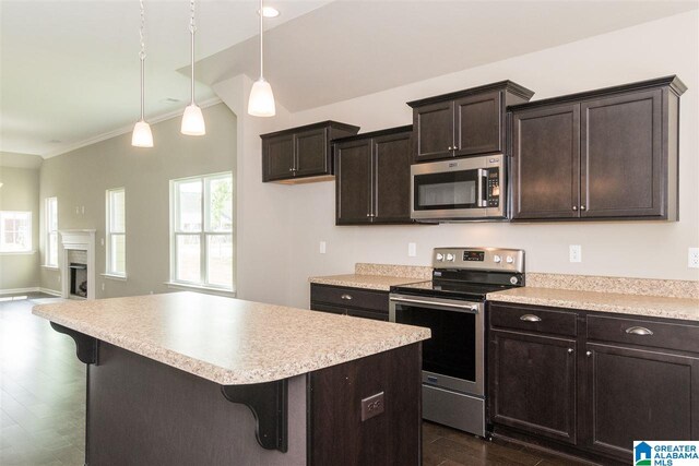 kitchen with crown molding, appliances with stainless steel finishes, hanging light fixtures, a breakfast bar area, and dark wood-type flooring