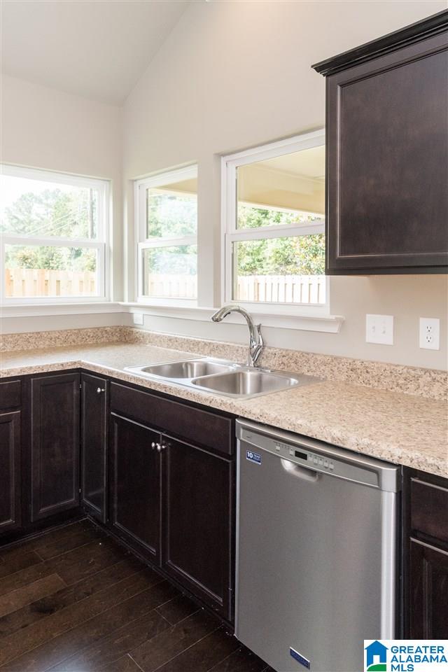 kitchen with dark hardwood / wood-style flooring, lofted ceiling, dark brown cabinetry, sink, and stainless steel dishwasher