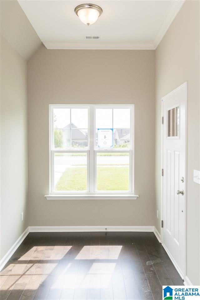 foyer featuring dark hardwood / wood-style flooring, vaulted ceiling, and crown molding