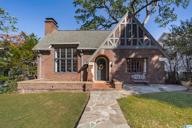 tudor-style house featuring a front yard