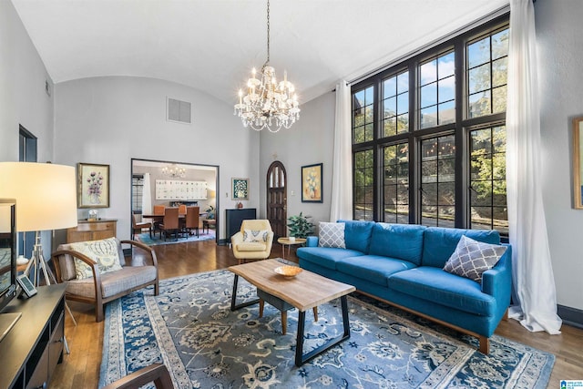 living room with high vaulted ceiling, hardwood / wood-style flooring, and an inviting chandelier