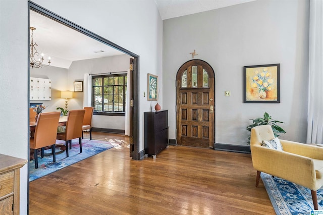 entrance foyer featuring hardwood / wood-style floors, a notable chandelier, and vaulted ceiling