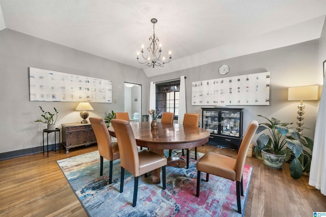 dining space featuring wood-type flooring, lofted ceiling, and a notable chandelier