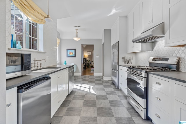 kitchen with appliances with stainless steel finishes, hanging light fixtures, decorative backsplash, sink, and white cabinets