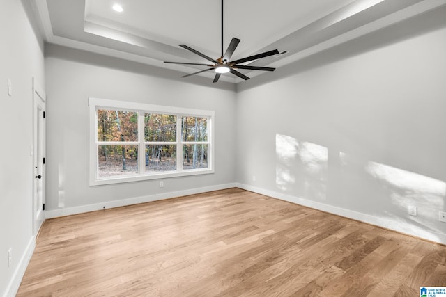 spare room featuring ceiling fan, a raised ceiling, and light hardwood / wood-style flooring