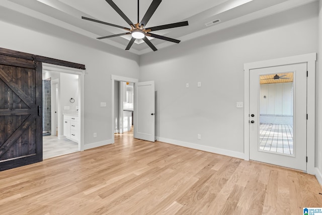 entrance foyer featuring ceiling fan, a barn door, and light wood-type flooring