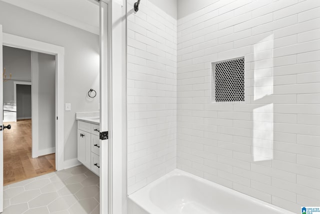 bathroom with tile patterned flooring, vanity, ornamental molding, and tiled shower / bath