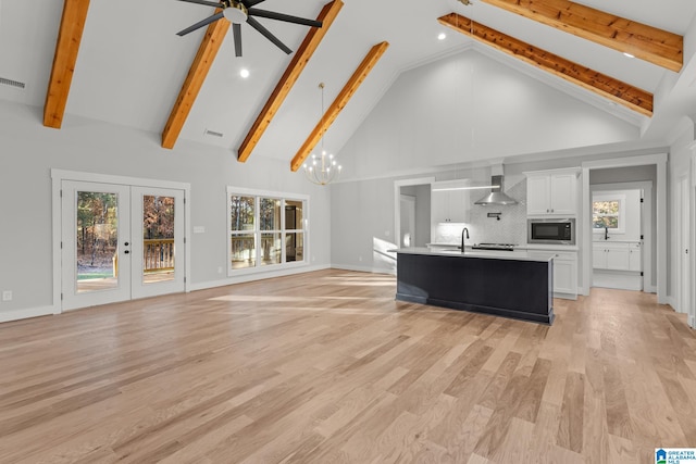 unfurnished living room with high vaulted ceiling, french doors, ceiling fan with notable chandelier, sink, and light hardwood / wood-style floors